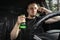 Drunk aggressive driver with a bottle of Alcohol driving a car, talk on the phone. Alcohol driving concept