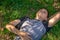 Drunk man with a bottle of alcohol under his arm resting on a green field