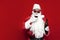 drunk santa claus in hat and festive glasses drinks wine from glass on red background