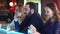 Drunk, tired businessman sitting at counter in bar with two young women