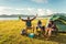 Drunken tourists doing party while camping and picnic in meadow field. Mountain and lake background. People and lifestyles concept