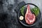 Dry aged cowboy or rib eye steak, raw beef meat with herbs. Black background. Top view. Copy space