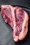 Dry-aged Raw T-bone or porterhouse beef marbled meat prime steak, on plate, on black wooden table background