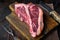 Dry-aged Raw T-bone or porterhouse beef marbled meat prime steak, on wooden cutting board, on old dark  wooden table background