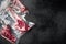 Dry aged steak in a vacuum. Meat products in plastic pack, tomahawk, t bone and club steak cuts, on black stone background, top