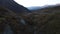 Dry autumn valley with river and mountains on the background. Footage. Aerial view of a curving stream flowing along