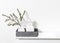 Dry branch of eucalyptus in a white figured earthenware vase. A pineapple figurine in a zinc tray on the table. Scandinavian style