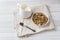 Dry Breakfast of oat flakes, granules and nuts. Muesli in a plate and a milk jug with yogurt.