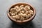 Dry cashew nuts in wood olive bowl on concrete background closeup