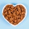 Dry cat food in the form of hearts lies in the saucer in the form of heart