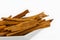 Dry cinnamon sticks in a small white ceramic dish isolated