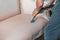 Dry cleaner& x27;s employee hand is cleaning classical sofa with professionally extraction method