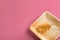 Dry crooked plant leaf of golden yellow color on a textured square plate of palm leaf against pastel pink background. Yellow pink