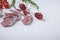 Dry cured fuet salami sausage slices with herbs on white textured background with space for text