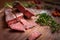 Dry-cured salami sliced on wooden background with grapes and herbs