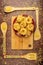 Dry fettuccine and Farfalle pasta in a red ceramic bowl on a bamboo cutting Board and bamboo spatulas on a wooden background