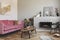 Dry flowers in pottery vase on small wooden table next to velvet pink couch in grey living room