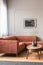 Dry flowers in stylish dark vase on coffee table in front of ginger colored corner sofa