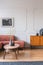 Dry flowers in stylish dark vase on wooden coffee table in front of ginger colored corner sofa