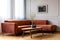 Dry flowers in stylish dark vase on wooden coffee table in front of ginger colored corner sofa