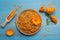 Dry and fresh calendula flowers on blue wooden table, flat lay