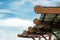 Dry grass hay roof with wooden design decorative elements on blue sky with light fluffy white clouds background