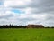 Dry haystacks big bale after harvest, mowing meadows, forest, green summer field, blue cloudy sky