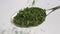 Dry herbal green seasoning parsley falls into a spoon.