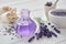 Dry lavender flowers, bottle of essential oil or flavored water, sachet and mortar on white table