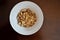 Dry muesli in a white plate on a brown wooden table