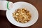 Dry muesli in a white plate on a brown wooden table. Kefir is poured into muesli