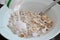 Dry muesli in a white plate on a brown wooden table. Kefir is poured into muesli