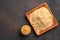 Dry mustard powder in a wooden plate and ready-made pasty mustard on a brown background. Minimalistic background with space to