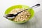 Dry oatmeal, spoon in green bowl on wooden table