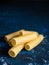 Dry pasta Tortiglioni closeup on a dark blue background.