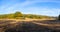 Dry pasture and autumnal colorful forest under blue sky