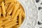 Dry penne pasta on blue white vintage plate, whole wheat uncooked ingredient