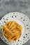 Dry penne pasta on blue white vintage plate, whole wheat uncooked ingredient