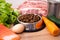 Dry pet dog food with natural ingredients. Raw meat, fish, vegetables, eggs and salad near bowl with dry pet feed. concept of a