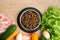 Dry pet dog food with natural ingredients. Raw meat, fish, vegetables, eggs and salad near bowl with dry pet feed on wooden