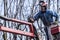 Dry pruning of trees by a man with a chainsaw, standing on a mechanical platform