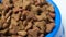Dry puppy food in a blue bowl rotates on a white background. A complete diet for pets