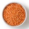 Dry red lentils in white ceramic bowl.