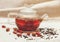 The Dry Red Small Roses with Black Tea in the Glass Teapot,Tea Drinking,Aromatized Flowers, Rough Linen Tableclose;Toned