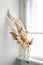 Dry reeds in ceramic vase on windowsill, vintage home interior