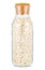 Dry rolled oats in a closed transparent glass bottle with cork lid isolated on white background