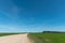 A dry sandy road passes through a field under the scorching sun and clouds. Dirt road outside the city in the village. Arid