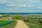 A dry sandy road passes through a field under the scorching sun and clouds. Dirt road outside the city in the village. Arid