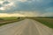 A dry sandy road passes through a field under the scorching sun and clouds. Dirt road outside the city in the village. Arid