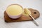 Dry semolina durum flour in a pink bowl over white wooden surface, side view. Close-up